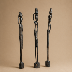 Tre sculture in legno scuro, stilizzate, raffiguranti figure femminili con contenitori sulla testa, su sfondo neutro.