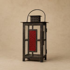 Lanterna decorativa rettangolare in metallo scuro con pannelli in vetro trasparente e un pannello rosso a rilievo, su sfondo beige.
