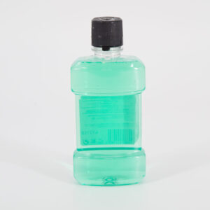 Flacone di collutorio in plastica trasparente con liquido verde acqua e tappo nero, visto da dietro su sfondo bianco.