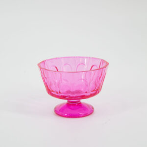 Coppetta decorativa in vetro o plastica traslucida di colore rosa intenso, con superficie sfaccettata e piedistallo, su sfondo bianco.