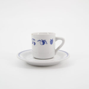 Set di tazza e piattino in ceramica bianca con decorazioni a frutta stilizzata blu e bordo blu, su sfondo bianco.