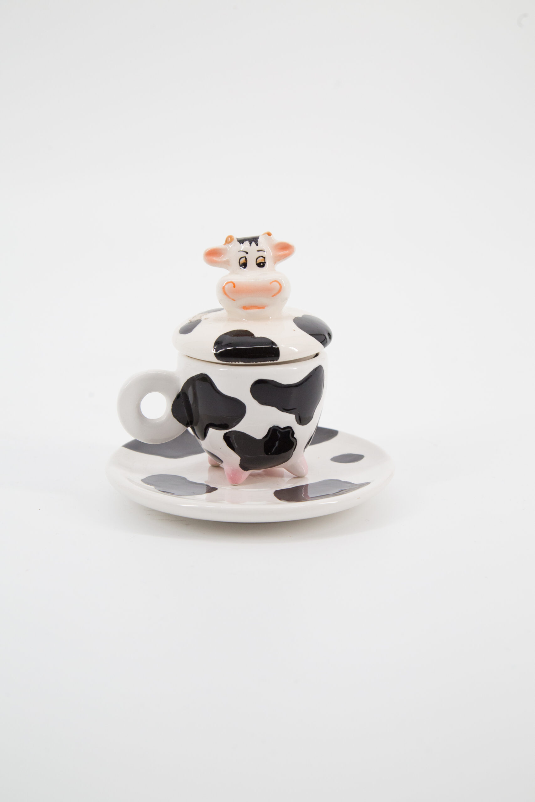 Set in ceramica bianco e nero con fantasia muccata, composto da tazza con zampe, coperchio con testa di mucca e piattino abbinato.