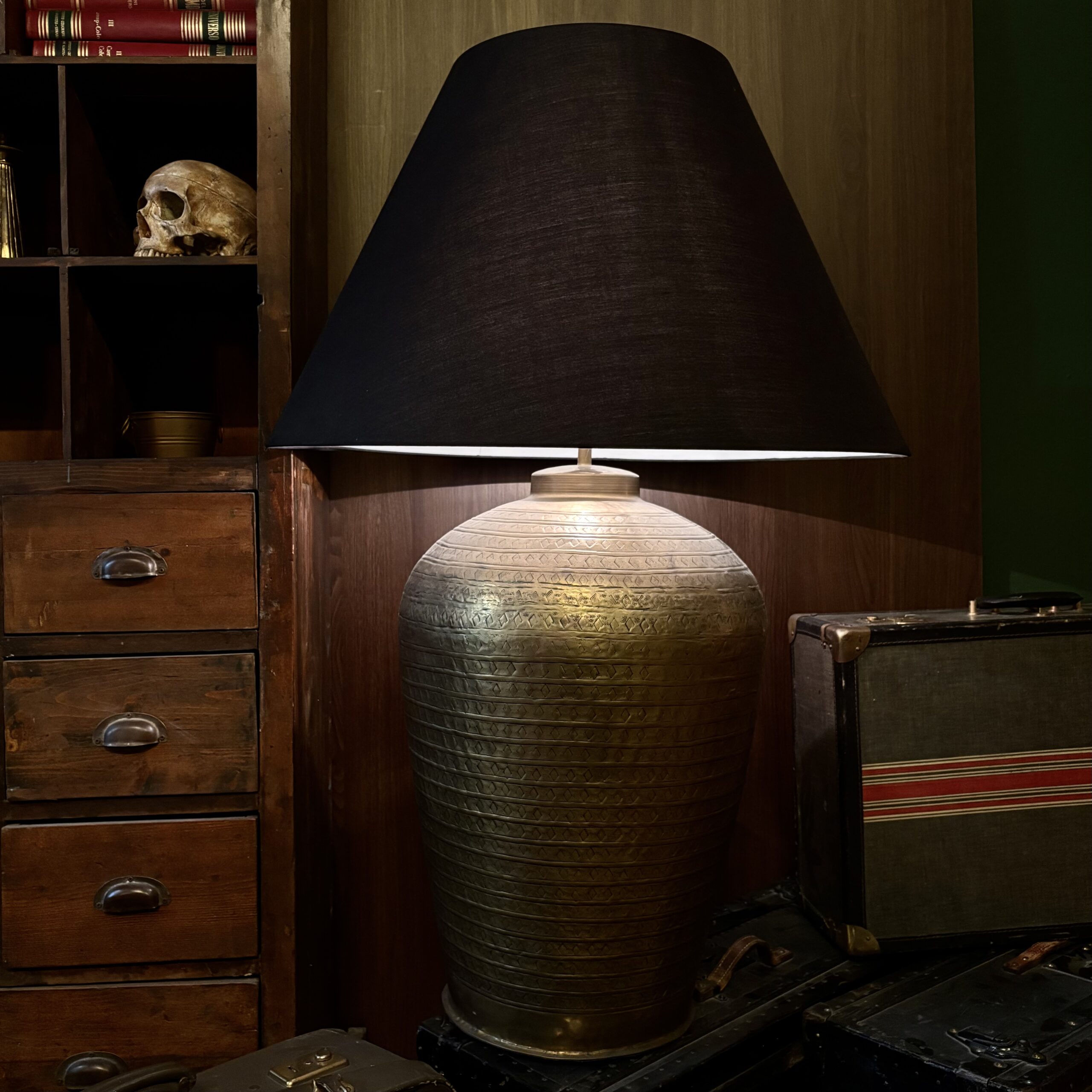 Grande lampada da terra vintage con paralume conico nero e base in metallo dorato inciso, posta accanto a un mobile in legno.