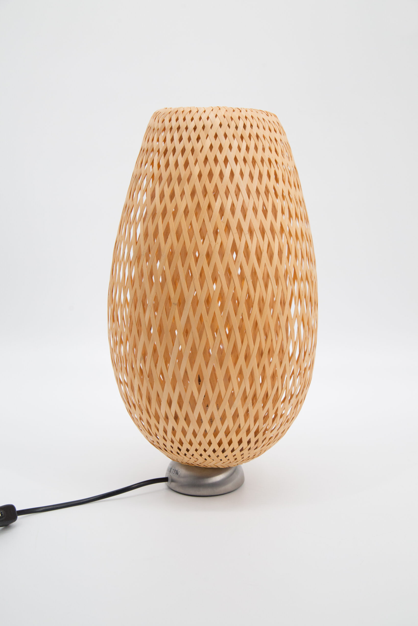 Lampada da tavolo con paralume in bambù intrecciato a trama diagonale e base metallica, su sfondo bianco.