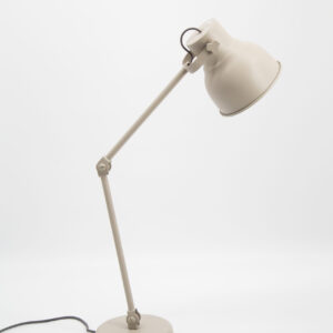 Lampada da tavolo articolata di colore beige chiaro su sfondo bianco, con braccio regolabile e paralume conico.