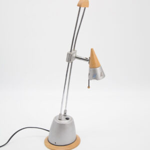 Lampada da tavolo con base conica in metallo grigio, fusto doppio cromato e paralume conico in legno e metallo traforato, su sfondo bianco.