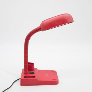Lampada da scrivania rossa con braccio flessibile e base rettangolare, vista laterale su sfondo bianco.