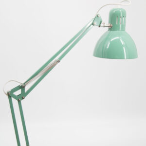 Lampada da scrivania articolata vintage di colore verde acqua, con braccio a molle e paralume a cupola, su sfondo bianco.