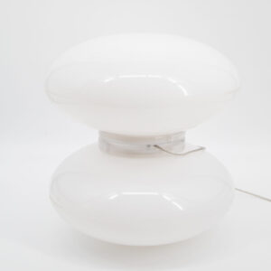 Lampada da tavolo bianca lucida a forma di fungo, con due sezioni ellissoidali sovrapposte e base trasparente, su sfondo bianco.