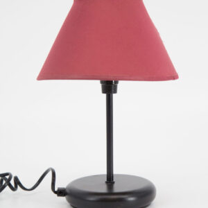 Lampada da tavolo con base e stelo neri e paralume conico in tessuto rosso bordeaux su sfondo bianco.