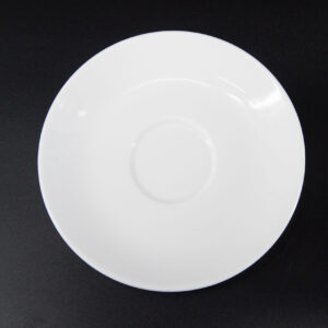 Piattino sottotazza bianco in ceramica o porcellana, visto dall'alto su sfondo nero, con incavo centrale per tazza.