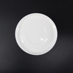 Un piattino bianco in ceramica, visto dall'alto, su uno sfondo nero, con una superficie liscia e lucida.