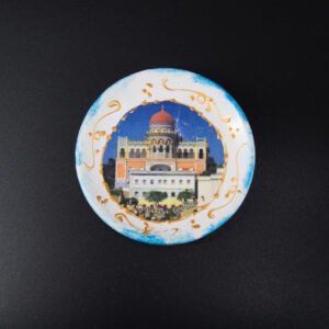 Piatto decorativo rotondo in ceramica con illustrazione del Palazzo Sticchi di S. Cesarea Terme e bordo blu e oro.