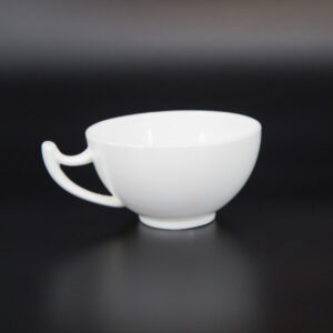 Tazza bianca opaca con manico curvo e design minimalista, fotografata su sfondo scuro.