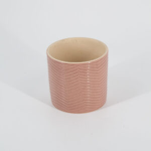Vaso cilindrico in ceramica rosa tenue con superficie testurizzata a motivo zigzag, interno beige, su sfondo bianco.
