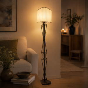 Piantana classica con struttura in ferro battuto scuro e paralume plissettato illuminato, in un ambiente interno caldo e accogliente.