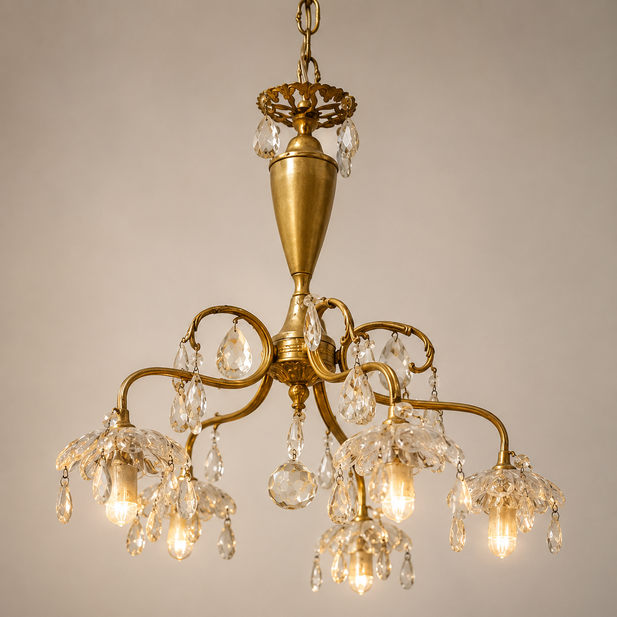 Lampadario classico a cinque luci con struttura in ottone dorato, pendenti in cristallo sfaccettato e coppe in vetro lavorato.