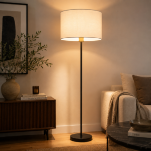 Lampada da terra moderna con fusto nero e paralume cilindrico in tessuto chiaro, accesa in un ambiente interno con arredi contemporanei.