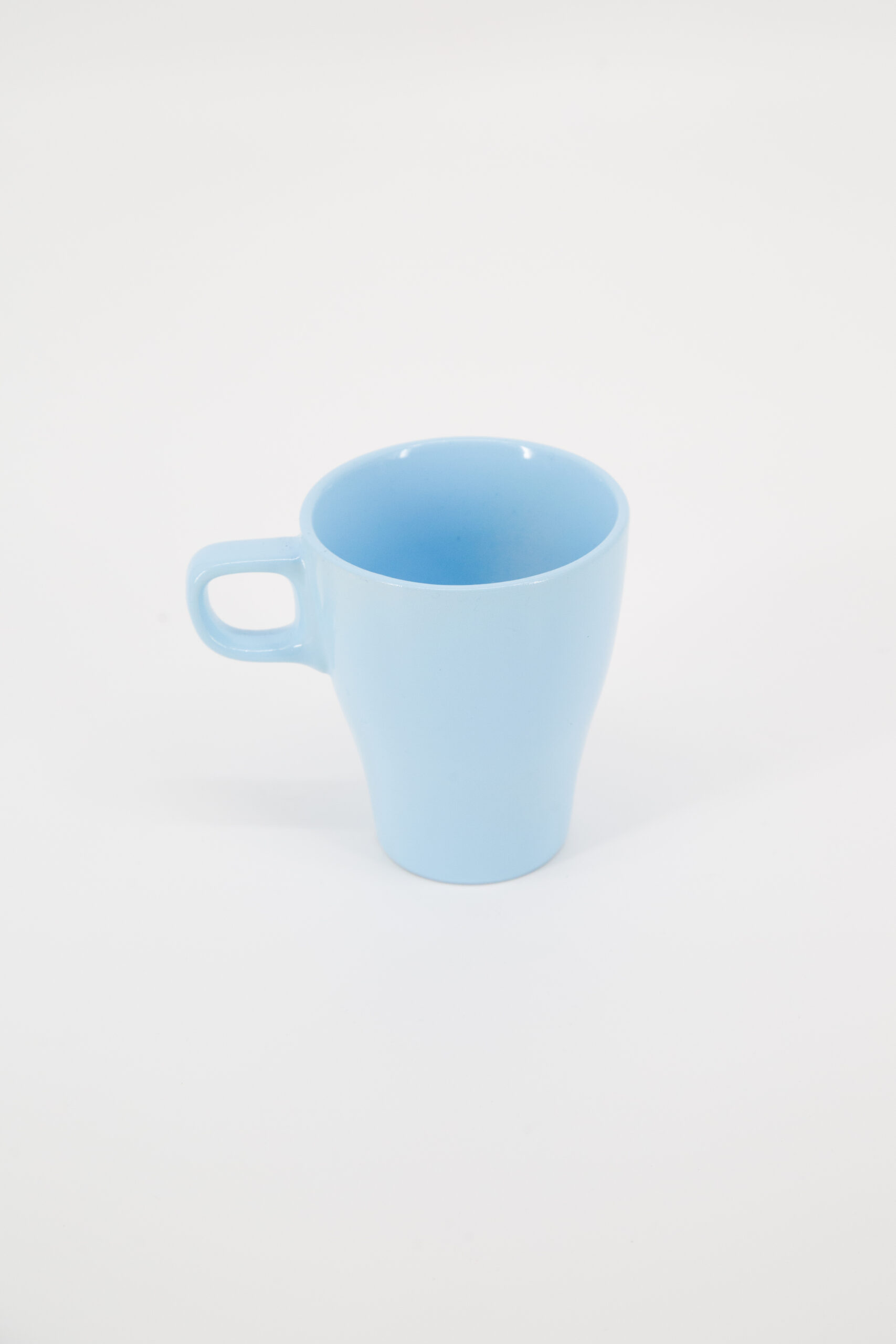 Tazza mug in ceramica di colore azzurro pastello con manico, fotografata su sfondo bianco neutro.