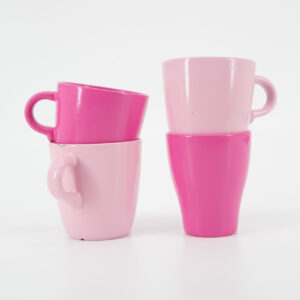 Quattro tazze in ceramica, due rosa chiaro e due fucsia, impilate a coppie su sfondo bianco, ideali come oggetti di scena.