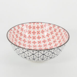 Ciotola in ceramica bianca con interno a fiori rossi e rosa e esterno a pattern geometrico nero, su sfondo bianco.