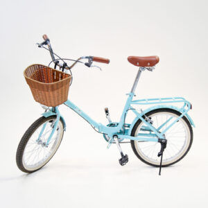 Bicicletta pieghevole color celeste con cesto in vimini anteriore, sella e manopole marroni, e portapacchi posteriore, su sfondo bianco. Ideale come oggetto di scena vintage.