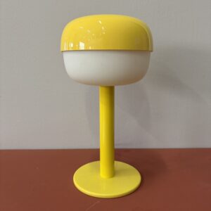Lampada da tavolo vintage con base e cupola superiore gialle lucide e diffusore centrale bianco opaco, su sfondo neutro.