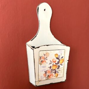 Portaoggetti da parete bianco in stile shabby chic con finitura distressed e decorazione di limoni e fiori.