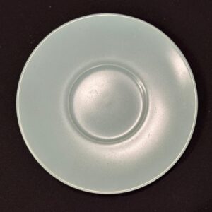 Piattino circolare in ceramica di colore azzurro pastello, con incavo centrale per tazza, su sfondo scuro.