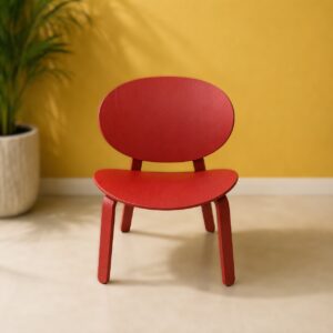 Sedia in legno multistrato laccato rosso con schienale e seduta arrotondati, su sfondo giallo con pianta verde.