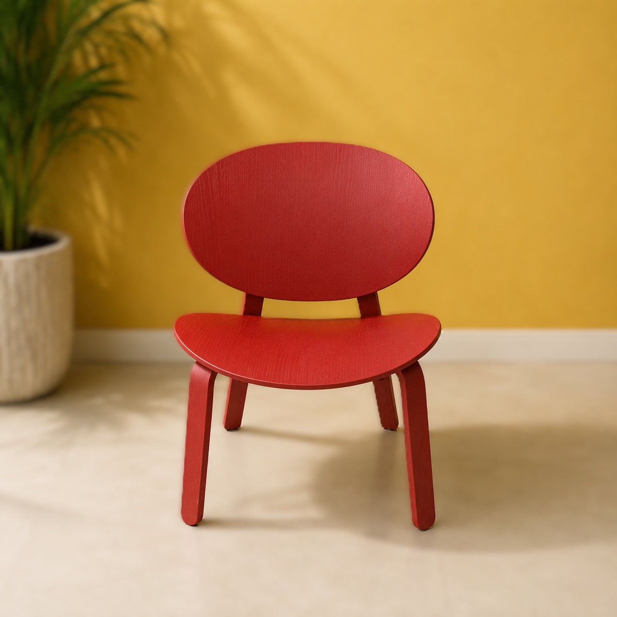 Sedia in legno multistrato laccato rosso con schienale e seduta arrotondati, su sfondo giallo con pianta verde.