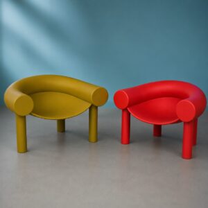 Due poltrone dal design curvilineo, una giallo senape e una rossa, su sfondo blu e pavimento grigio.