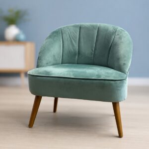 Poltroncina accentata in velluto verde acqua con schienale a coste e gambe affusolate in legno, su pavimento chiaro.