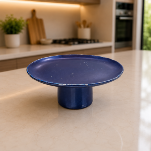 Alzatina blu scuro con finitura effetto invecchiato, posta su un bancone da cucina moderno. Dettagli di usura visibili.
