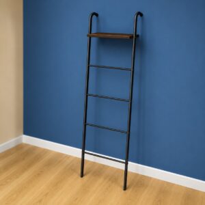 Scaffale a scala decorativo con struttura in metallo nero e ripiano in legno marrone, appoggiato a una parete blu.