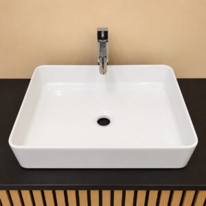 Lavabo rettangolare bianco in ceramica con rubinetto monocomando cromato, installato su un mobile scuro con base a doghe di legno.