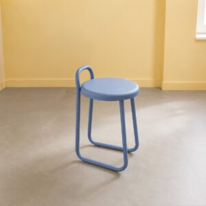 Sgabello monoblocco blu pastello con seduta rotonda e schienale curvo, su pavimento grigio chiaro con parete gialla.