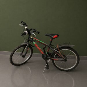 Bicicletta mountain bike nera con dettagli rossi e verdi, parafanghi e portapacchi, appoggiata su cavalletto davanti a parete verde.