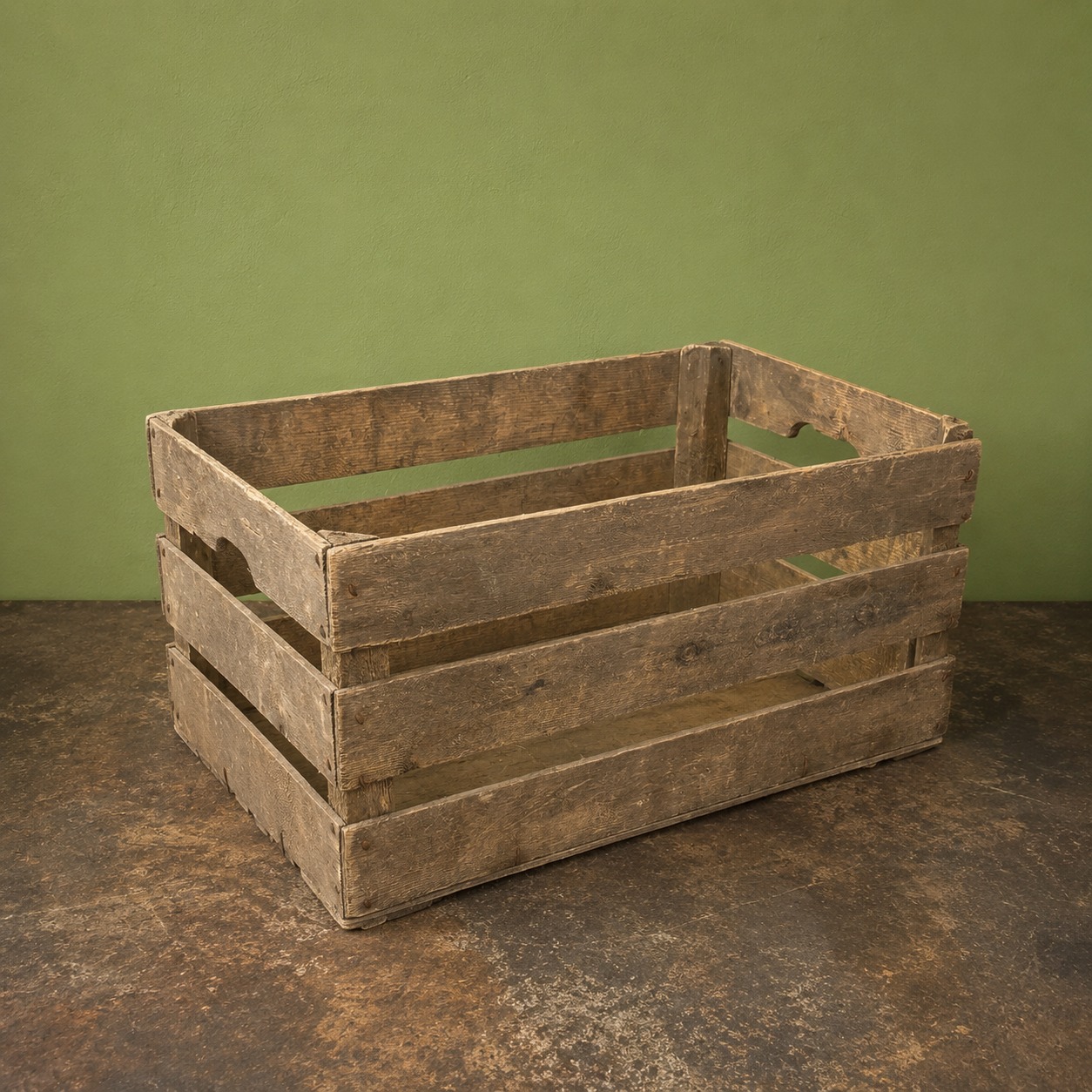 Cassetta in legno scuro, rustica e invecchiata, con doghe orizzontali e maniglie intagliate, su sfondo verde e superficie scura.