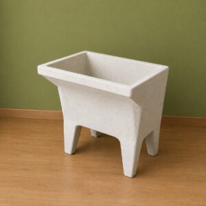 Lavatoio freestanding moderno in composito effetto graniglia, di colore chiaro, con design minimalista e quattro gambe integrate, su pavimento in legno con parete verde.