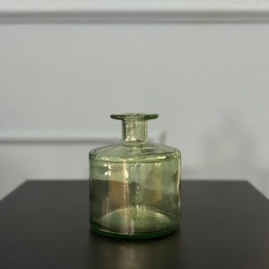 Vaso decorativo in vetro di colore verde tenue, con corpo cilindrico e collo stretto, posizionato su una superficie scura.