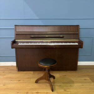 Pianoforte verticale marrone scuro Furstein Farfisa con tastiera e sgabello in legno con seduta nera, su pavimento in legno.