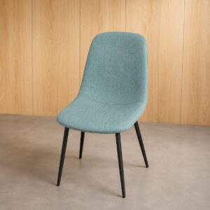 Sedia moderna imbottita in tessuto azzurro-verde acqua con gambe affusolate in metallo nero, su sfondo di pannelli in legno chiaro.
