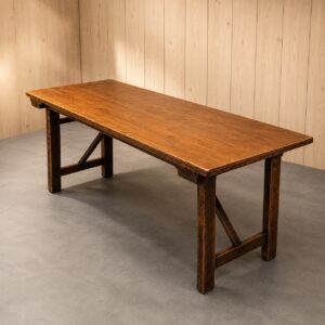 Lungo tavolo rettangolare in legno massello con finitura rustica marrone scuro, gambe robuste e traverse di rinforzo.
