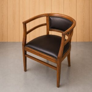 Sedia a pozzetto classica in legno scuro con schienale e seduta rivestiti in similpelle nera e borchie decorative.