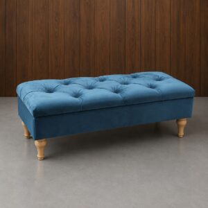 Panca contenitore rettangolare in velluto blu petrolio con lavorazione capitonné e quattro gambe tornite in legno chiaro, su sfondo in legno scuro.