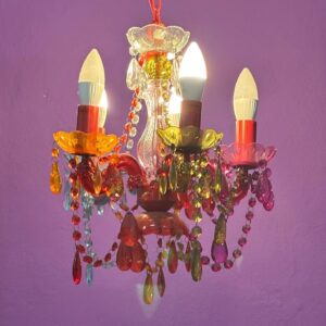 Lampadario a tre bracci con struttura in acrilico, decorato con pendenti e perline multicolori su sfondo viola.