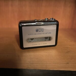 Lettore di cassette USB portatile Tonor nero e argento con dettagli cromati, posizionato su una superficie di legno.