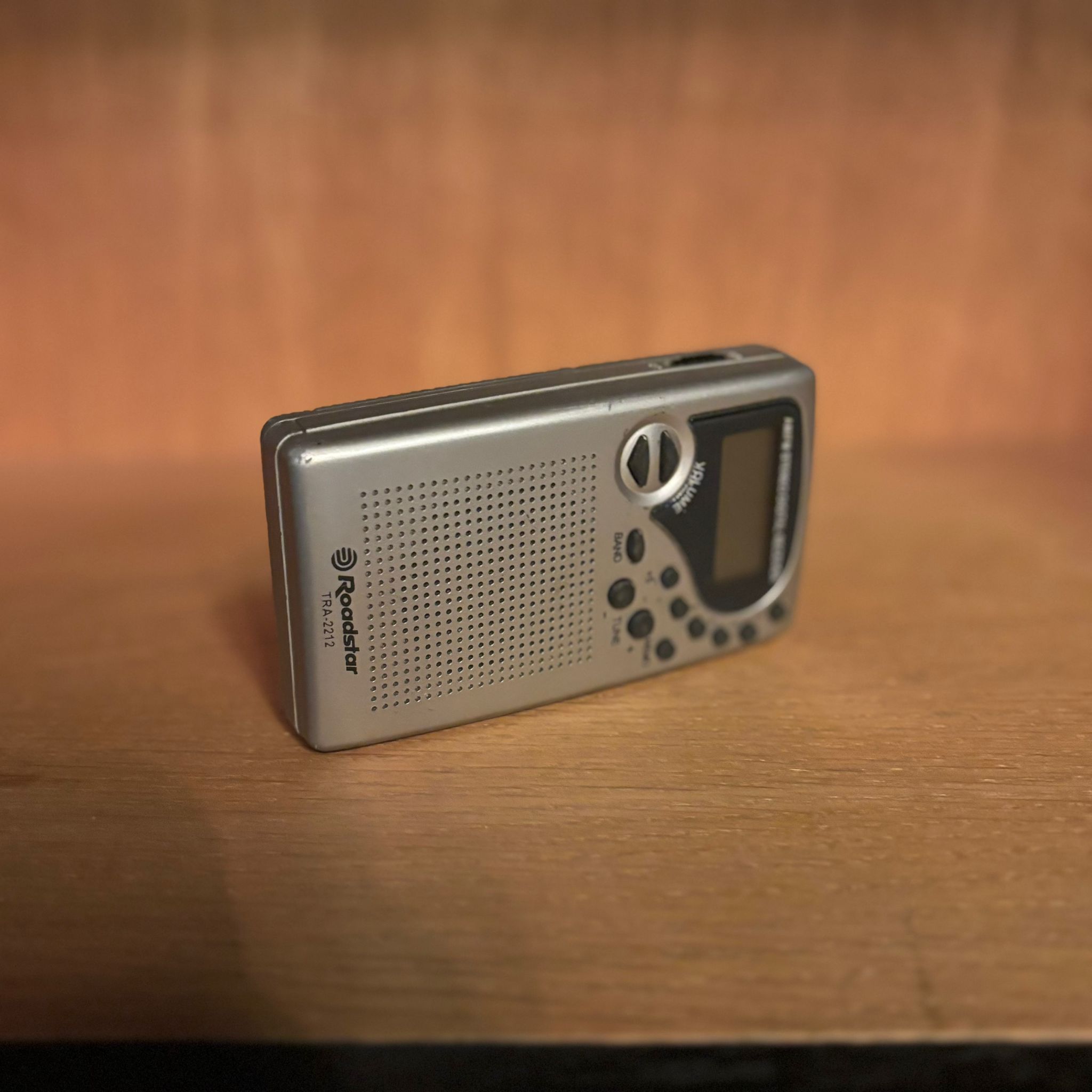 Radio portatile Roadstar TRA-2212 di colore argento, con griglia altoparlante e controlli, posizionata su una superficie di legno.