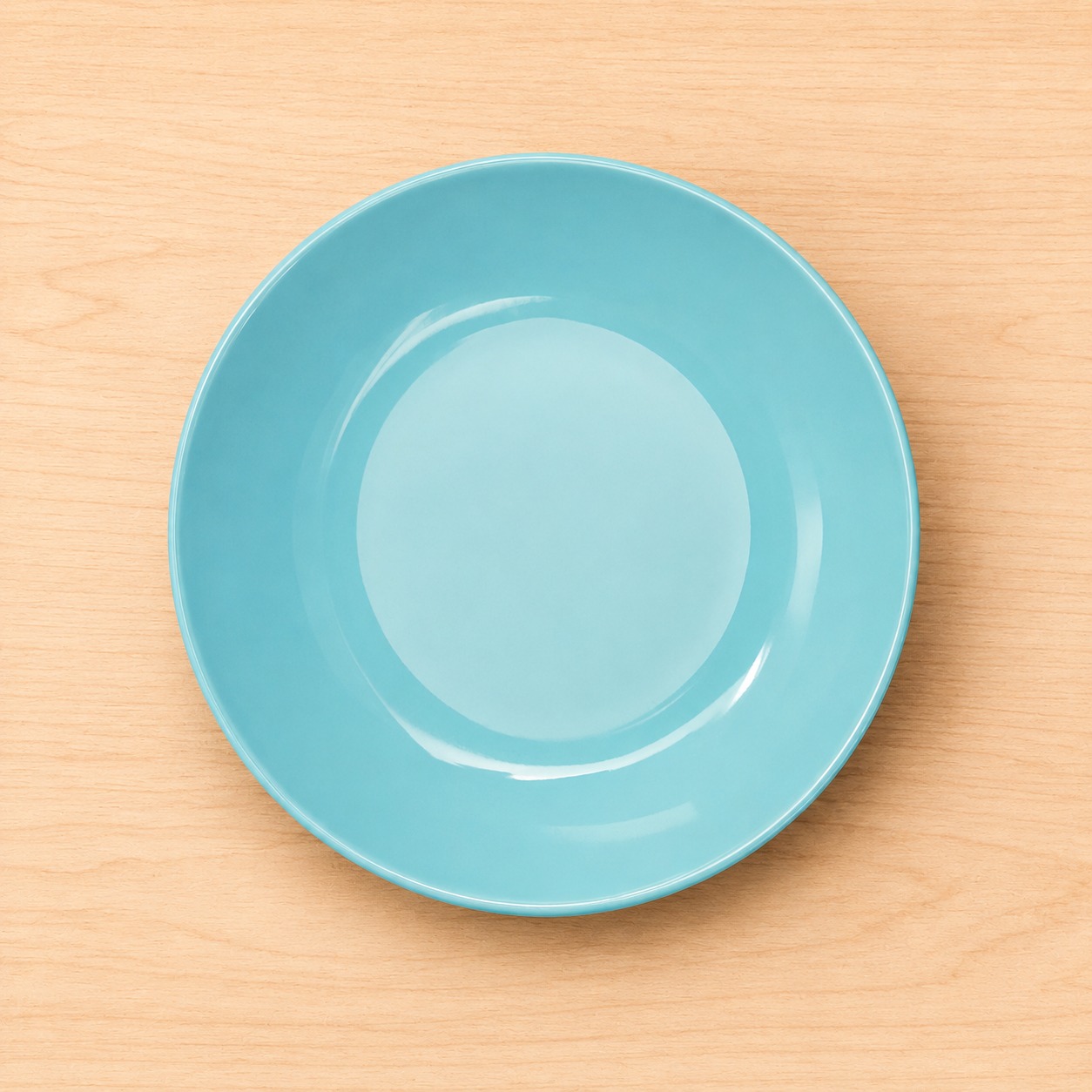 Un piatto fondo rotondo di colore azzurro chiaro, posizionato centralmente su una superficie di legno chiaro.